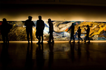 An undergraduate English class views a mural at the Tufts University Art Galleries.