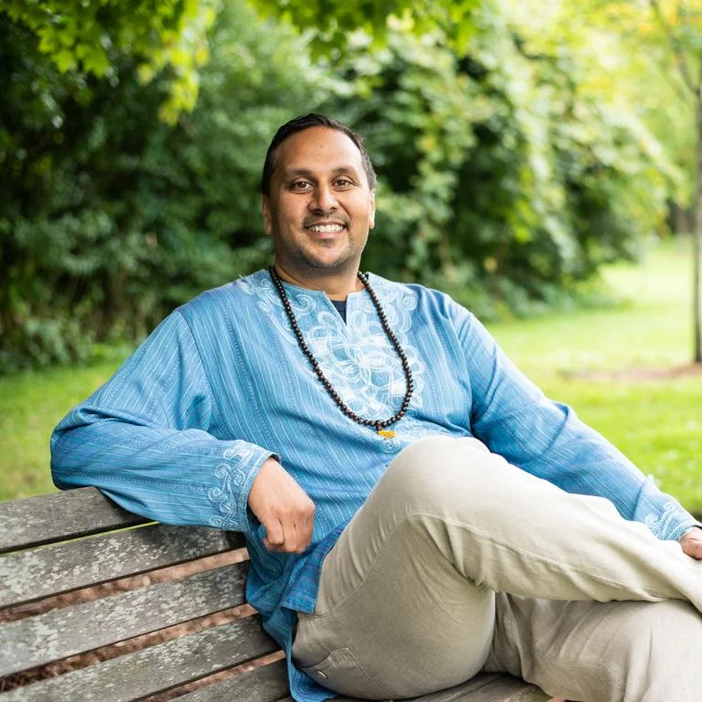 Amer F. Ahmed, the vice provost for diversity, equity, and inclusion and chief diversity officer at the University of Vermont, sits outside on a bench and smiles at the camera.