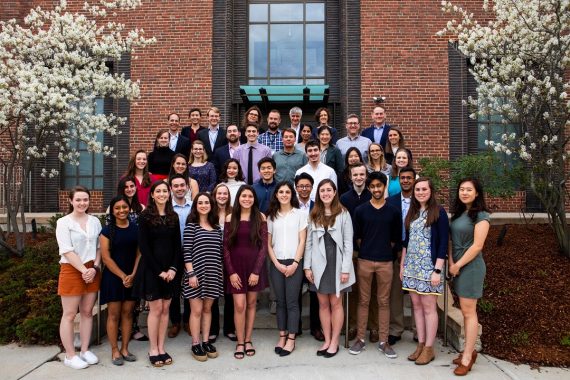 Scholars and mentors from the second cohort of Laidlaw scholars pose outside on steps outside of a brick building.