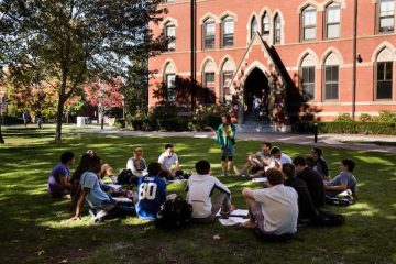 A professor teaches a class outside on the green.